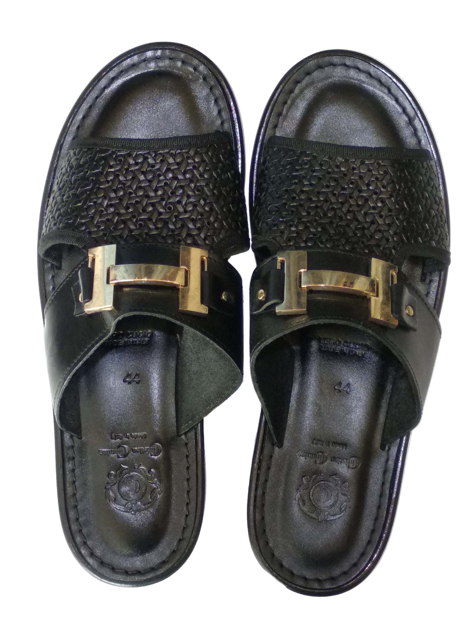 Pair of black sandals with gold buckles on a white background